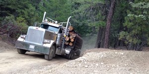 Two log trucks coming over a hill